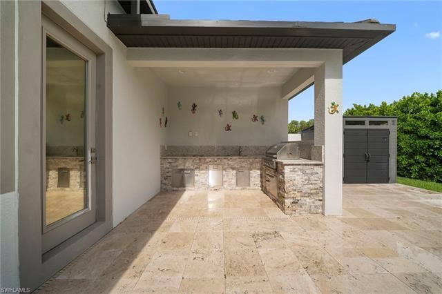 9796 Strike Ln, Bonita Springs, FL 34135 Expansive outdoor living area featuring a built-in grill, stone veneer cabinetry, stone countertops, and natural stone flooring