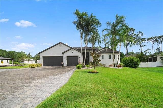 9796 Strike Ln, Bonita Springs, FL 34135 Stucco exterior with a tiled roof, paver driveway, two dark garage doors, and mature palm trees