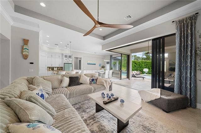 9796 Strike Ln, Bonita Springs, FL 34135 Vaulted ceiling with an integrated ceiling fan, recessed lighting, tile flooring, and multi-panel sliding glass doors opening to an outdoor area with a pool
