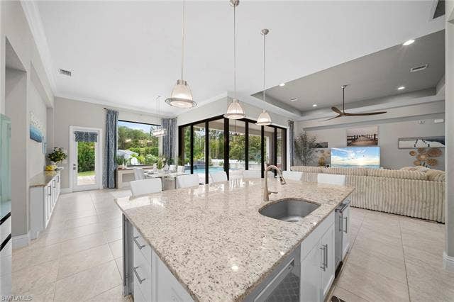 9796 Strike Ln, Bonita Springs, FL 34135 Kitchen island with a built-in sink, granite countertop, and pendant lighting