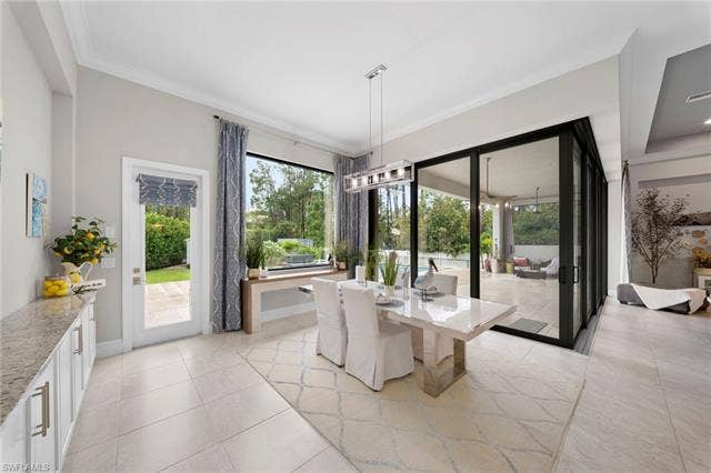 9796 Strike Ln, Bonita Springs, FL 34135 Spacious interior featuring large format tile flooring, a built-in buffet with light-toned countertops, expansive floor-to-ceiling windows, and multi-panel sliding glass doors