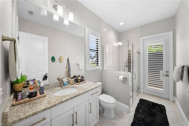 9796 Strike Ln, Bonita Springs, FL 34135 White shaker-style vanity with granite countertop, undermount sink, and brushed brass hardware