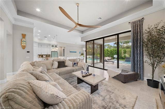 9796 Strike Ln, Bonita Springs, FL 34135 Tray ceiling with recessed lighting, large format wood-finish flooring, sliding glass doors to outdoor living space, contemporary ceiling fan, and open concept design