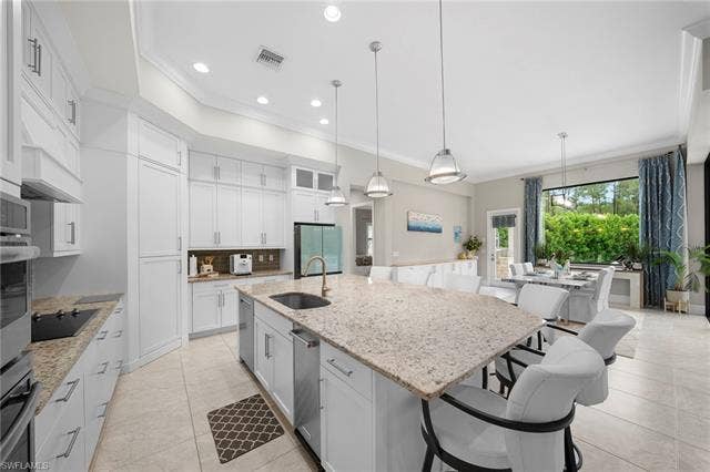 9796 Strike Ln, Bonita Springs, FL 34135 Open-concept kitchen featuring white cabinetry, light-toned countertops, a center island with sink, and recessed lighting