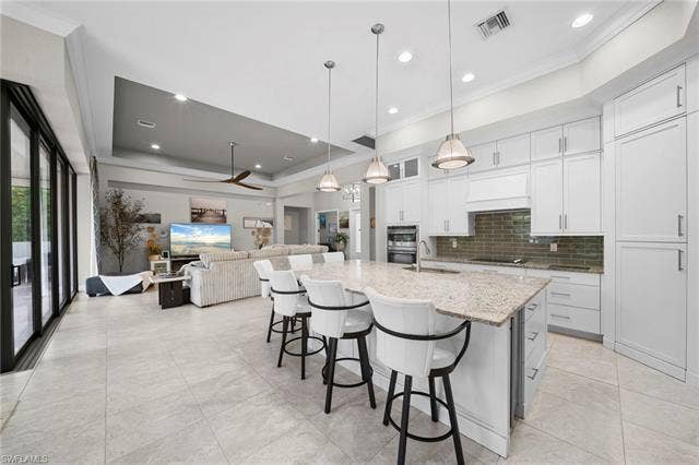 9796 Strike Ln, Bonita Springs, FL 34135 Spacious open-concept living area featuring large format tile flooring, a tray ceiling, and a ceiling fan