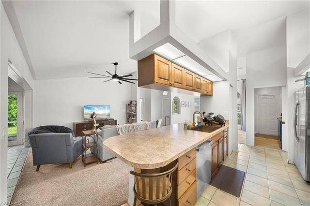 3730 21st Pl, Cape Coral, FL 33914 Vaulted ceilings, kitchen island with seating, wood-finish cabinetry, stainless steel dishwasher, and tiled flooring