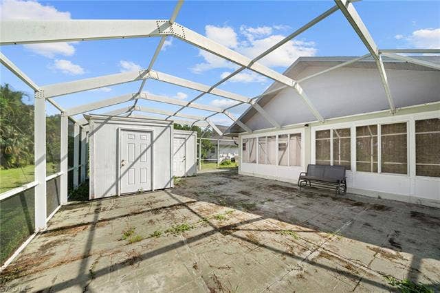 3730 21st Pl, Cape Coral, FL 33914 Expansive screened enclosure featuring a concrete patio, two utility sheds, and direct access to an enclosed sunroom