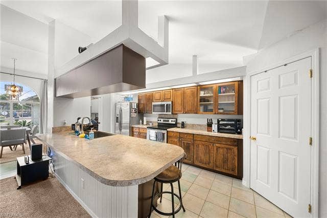 3730 21st Pl, Cape Coral, FL 33914 Kitchen featuring wood cabinetry, integrated stainless-steel appliances, and a breakfast bar with beadboard paneling