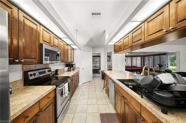 3730 21st Pl, Cape Coral, FL 33914 Galley kitchen featuring wood cabinetry, stainless steel appliances, light-toned countertops, and tiled flooring