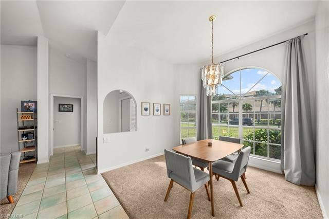 3730 21st Pl, Cape Coral, FL 33914 Vaulted ceilings, arched wall opening, tiled flooring, large arched window, and a chandelier lighting fixture
