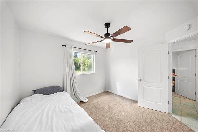3730 21st Pl, Cape Coral, FL 33914 Carpeted room featuring a ceiling fan with integrated lighting, a window with a dark curtain rod, and a white paneled door