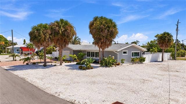 310 Madison Ct, Fort Myers Beach, FL 33931 Single-story residence featuring a light gray exterior, white trim, and a white fence