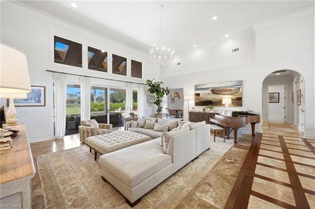 1936 Empress Ct, Naples, FL 34110 High ceilings with upper transom windows, multiple sliding glass doors, recessed lighting, and a chandelier illuminate the living area