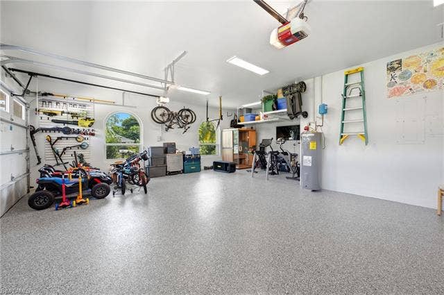 1936 Empress Ct, Naples, FL 34110 Spacious 3 car garage with light gray epoxy flooring, white walls, and arched windows