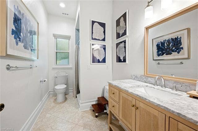 1936 Empress Ct, Naples, FL 34110 Bathroom featuring a wood-finish vanity with a stone countertop, walk in shower, an undermount sink, and a framed mirror
