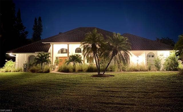 1936 Empress Ct, Naples, FL 34110 Stucco exterior with arched windows, a covered entry, and a tile roof