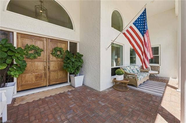 1936 Empress Ct, Naples, FL 34110 Front Entrance with brick paver porch with double wood entry doors, arched transom window, and adjacent windows