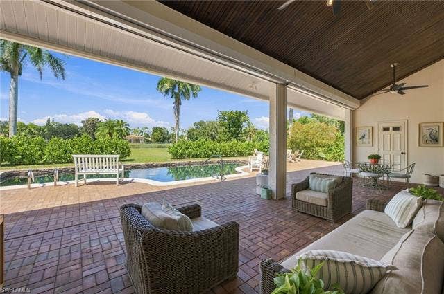 1936 Empress Ct, Naples, FL 34110 Expansive brick paver patio featuring a swimming pool, outdoor shower, with a surrounding large lawn looking at lake view.