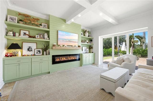 1936 Empress Ct, Naples, FL 34110 Built-in cabinetry and shelving surround a linear fireplace, tile flooring, sliding glass doors out to patio and pool area