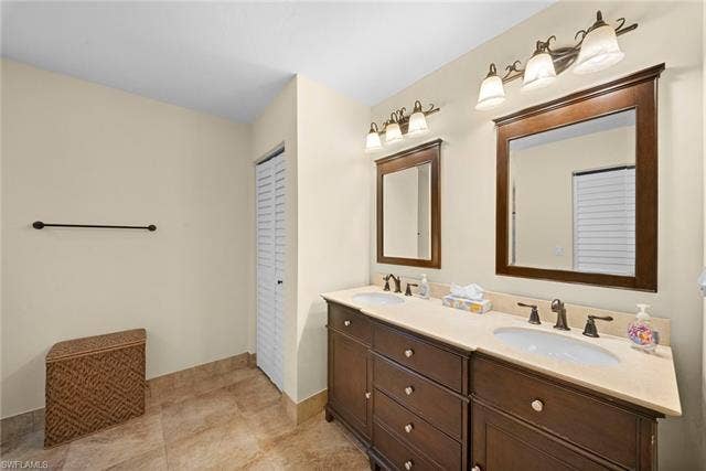 2171 Kings Lake Blvd, Naples, FL 34112 Double vanity with dark wood cabinetry, light-colored countertops, and integrated sinks