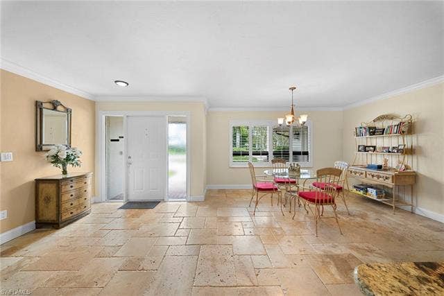 2171 Kings Lake Blvd, Naples, FL 34112 Recessed and pendant lighting illuminate the entry and dining areas, featuring natural stone tile flooring and crown molding
