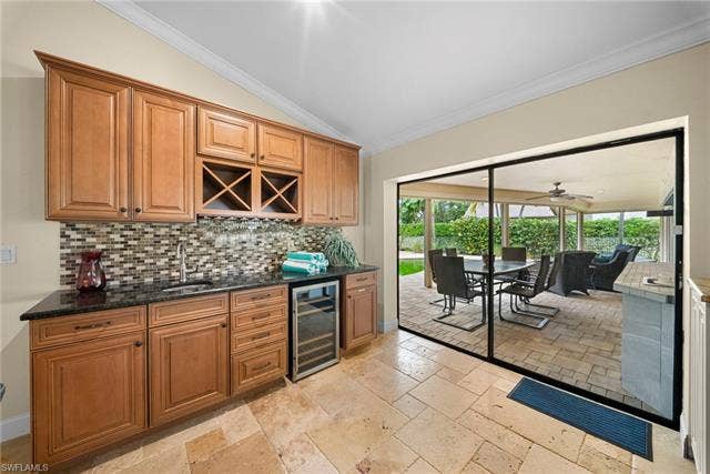 2171 Kings Lake Blvd, Naples, FL 34112 Built-in cabinetry with integrated wine storage, mosaic tile backsplash, black countertop, and a built-in beverage cooler