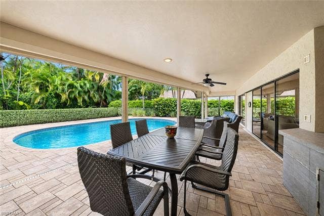 2171 Kings Lake Blvd, Naples, FL 34112 Covered patio with recessed lighting, ceiling fan, paved flooring, and an oval swimming pool with lush landscaping