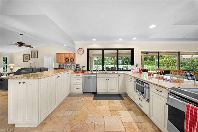 2171 Kings Lake Blvd, Naples, FL 34112 Travertine-style tile flooring, extensive light-toned cabinetry, light-toned countertops, stainless steel appliances, and large windows