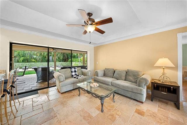 2171 Kings Lake Blvd, Naples, FL 34112 Tray ceiling with crown molding, ceiling fan, large format tile flooring, and sliding glass doors leading to an outdoor paved patio