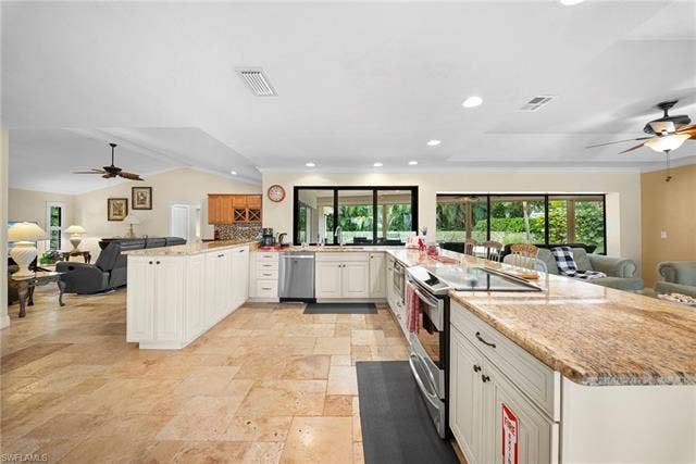 2171 Kings Lake Blvd, Naples, FL 34112 Spacious kitchen featuring an extended island, integrated stovetop, light cabinetry, stone countertops, and tile flooring