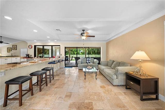 2171 Kings Lake Blvd, Naples, FL 34112 Expansive tile flooring, tray ceiling, recessed lighting, and a large breakfast bar with granite countertop