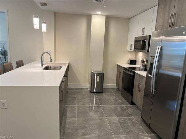 26600 Rosewood Pointe Dr, #B-107, Bonita Springs, FL 34135 Kitchen with white cabinetry, sink, a kitchen breakfast bar, decorative light fixtures, and appliances with stainless steel finishes