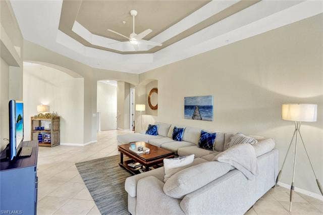 10060 Valiant Ct, #202, Miromar Lakes, FL 33913 Living area featuring a tray ceiling with a ceiling fan, arched doorways, and tile flooring