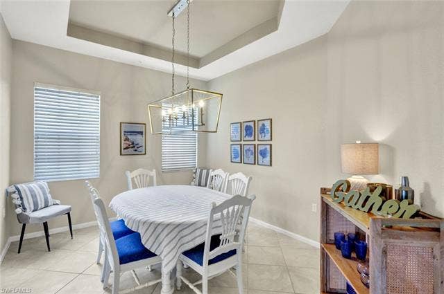 10060 Valiant Ct, #202, Miromar Lakes, FL 33913 Tray ceiling with a suspended chandelier, two windows with blinds, and tile flooring