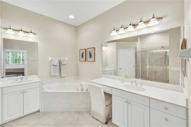 10060 Valiant Ct, #202, Miromar Lakes, FL 33913 Spacious bathroom featuring a corner soaking tub, dual vanity areas with white cabinetry, and a large walk-in shower with glass enclosure