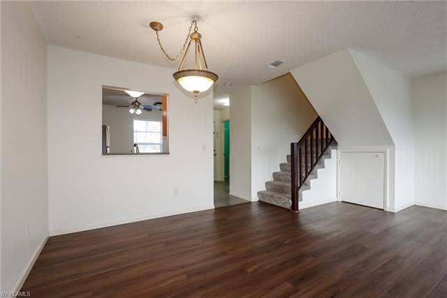 25484 Cockleshell Dr, #901, Bonita Springs, FL 34135 Unfurnished living room featuring dark wood finished floors, stairway, and a ceiling fan