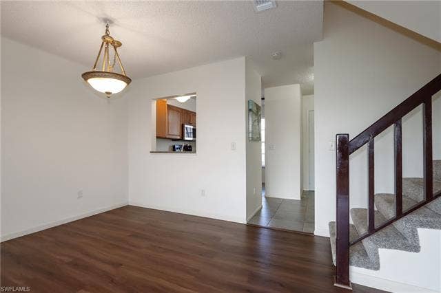 25484 Cockleshell Dr, #901, Bonita Springs, FL 34135 Unfurnished room with dark wood-type flooring, stairway, and a textured ceiling