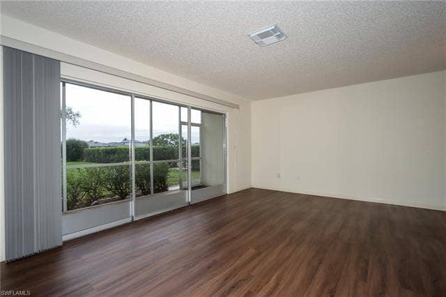 25484 Cockleshell Dr, #901, Bonita Springs, FL 34135 Unfurnished room featuring dark wood-type flooring and a textured ceiling