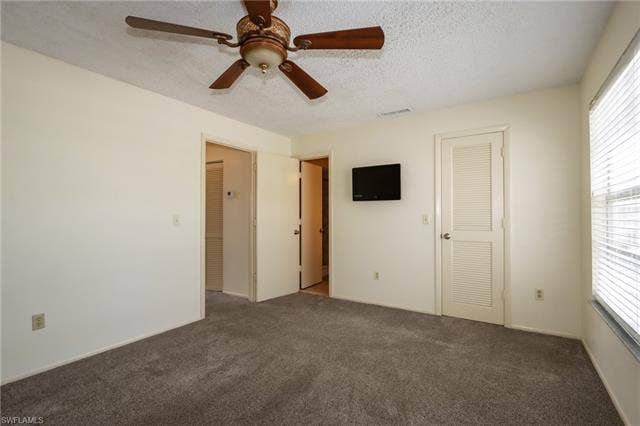 25484 Cockleshell Dr, #901, Bonita Springs, FL 34135 Unfurnished bedroom with a textured ceiling, carpet flooring, a ceiling fan, and a closet