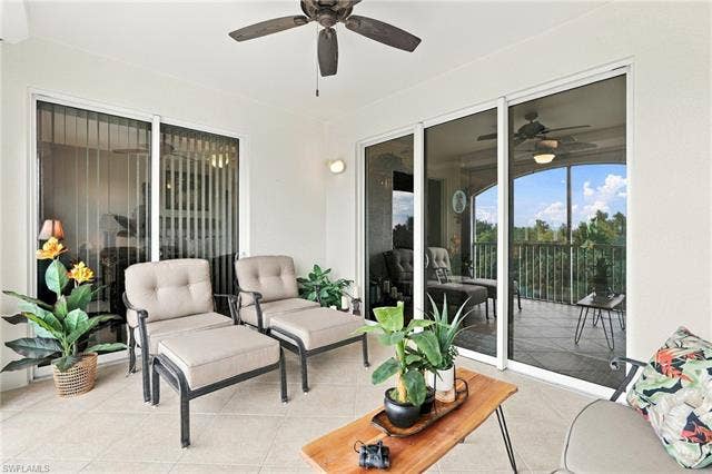 11041 Gulf Reflections Dr, #403, Fort Myers, FL 33908 Screened balcony featuring a ceiling fan, sliding glass doors, exterior wall sconce, and tile flooring
