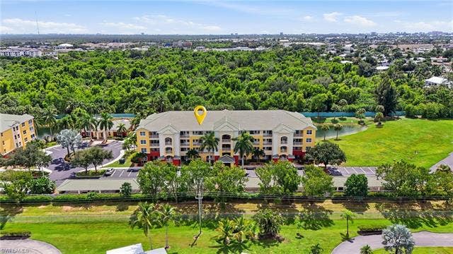 11041 Gulf Reflections Dr, #403, Fort Myers, FL 33908 Multi-story building with a light-colored exterior and red accents, surrounded by mature trees and manicured green spaces