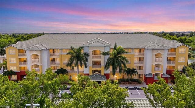 11041 Gulf Reflections Dr, #403, Fort Myers, FL 33908 Multi-story building featuring balconies, a tiled roof, and lush perimeter landscaping