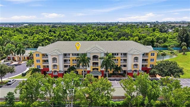 11041 Gulf Reflections Dr, #403, Fort Myers, FL 33908 Four-story building with multiple balconies, a green shingle roof, and a beige and yellow facade