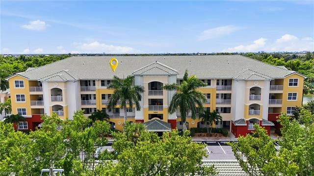 11041 Gulf Reflections Dr, #403, Fort Myers, FL 33908 Multi-story building featuring balconies, a tile roof, and a covered entrance