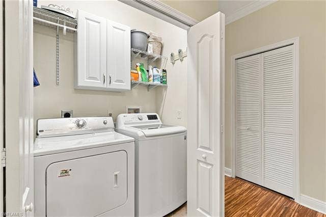 11041 Gulf Reflections Dr, #403, Fort Myers, FL 33908 Dedicated laundry area featuring white cabinetry, wire shelving, and wood-finish flooring