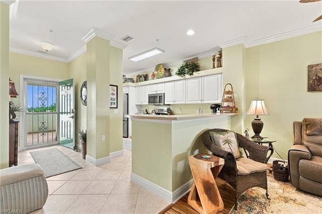 11041 Gulf Reflections Dr, #403, Fort Myers, FL 33908 Tile flooring, crown molding, white kitchen cabinetry, stainless steel appliances, and a breakfast bar