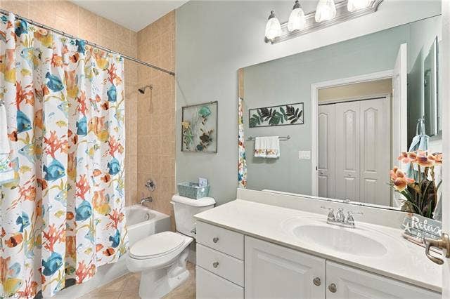 11041 Gulf Reflections Dr, #403, Fort Myers, FL 33908 Vanity with white cabinetry and integrated sink, full-width mirror, light-colored wall tiling in shower, built-in bathtub, and bi-fold closet doors