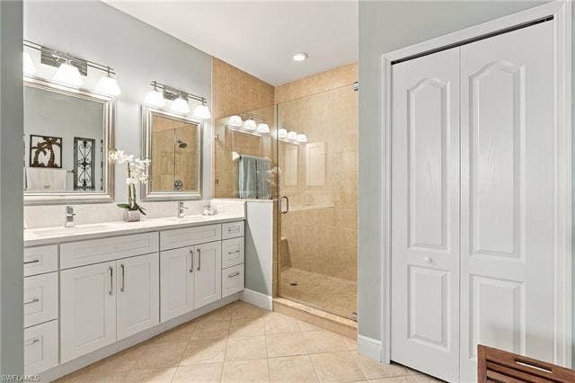 11041 Gulf Reflections Dr, #403, Fort Myers, FL 33908 Dual vanity with white cabinetry and integrated sinks, a tiled shower enclosure with glass panels, and tiled flooring