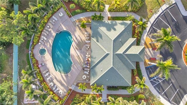 11041 Gulf Reflections Dr, #403, Fort Myers, FL 33908 Resort-style pool with integrated spa, extensive poolside patio, lush landscaping with mature palm trees, and an expansive parking area