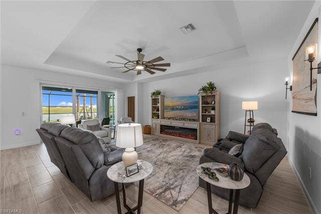 44810 Marina Ln, Punta Gorda, FL 33982 Tray ceiling with a ceiling fan, wood-finish tile flooring, built-in entertainment center, and sliding glass doors